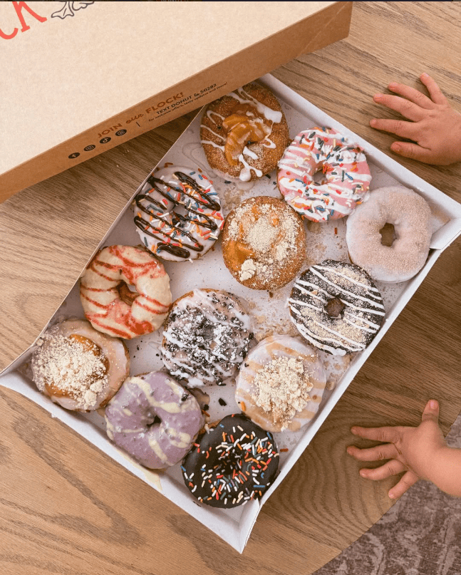Close-up of fresh donuts with dessert sauces and coffee for breakfast at Duck Donuts.